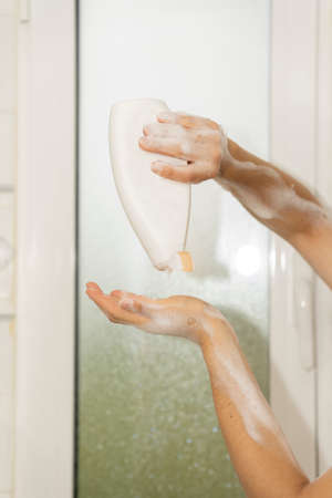 Pouring shower gel into her hand.