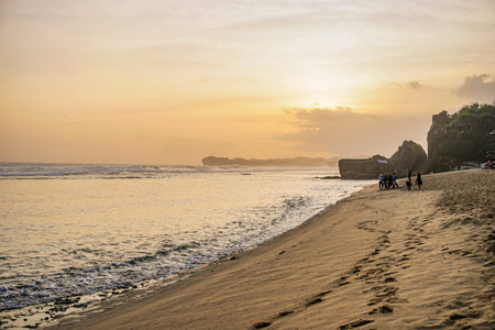 The atmosphere of the sunset on indrayanti beach. A group of visitors are seen enjoying the sun teggelam on indrayanti beach.の写真素材