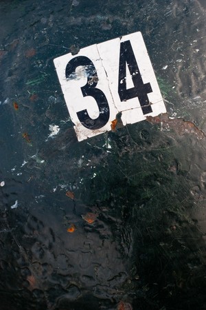 Detail closeup of a number on a black and green piece of metal with chipped paint.