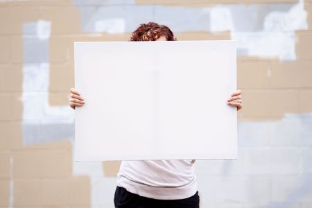 An anonymous girl holds a large white canvas sign with room for text or copy space.の写真素材