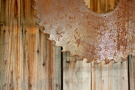 A rusty saw blade is hung on a wood wall to create an interesting and unique abstract background image with plenty of copy space for design の写真素材