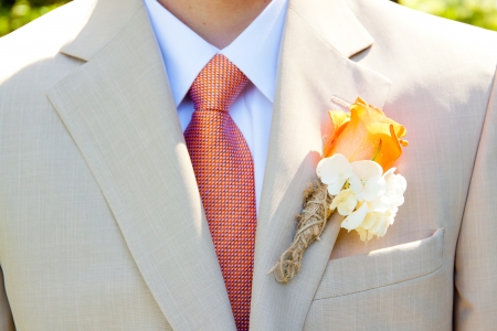 A groom in a light-colored suit is ready for his wedding day in formal attire with a boutineer on his jacket lapel.の写真素材