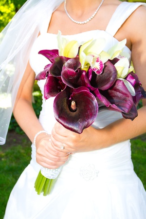 A beautiful bride in her white wedding dress holds her bouquet of flowers on her wedding day.の写真素材