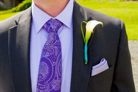 A groom and his boutonniere on his wedding day  He is wearing a suit with a single flower on the lapel of his jacket の写真素材