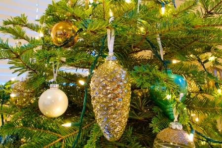 Elegant beautiful Christmas tree ornaments hang from this fir with lights and decorations all around.の写真素材