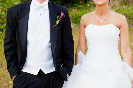 A fashionable bride and groom stand outdoors side by side and pose for some wedding pictures.の写真素材
