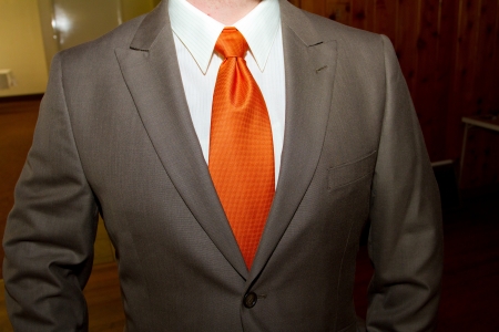 A groom wears a brown suit and an orange tie on his wedding day.の写真素材