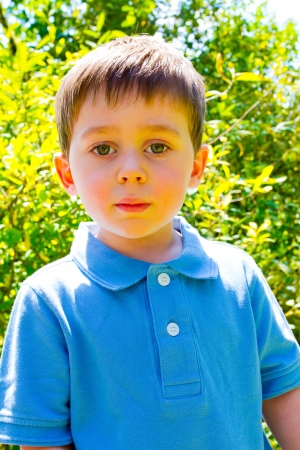 A young boy is playing outdoors while wearing a blue polo shirt.の写真素材