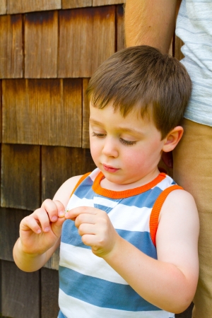 A boy is playing with an object outdoors while standing with his father.の写真素材