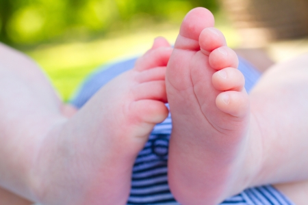The feet of a newborn baby photographed from below outdoors の写真素材