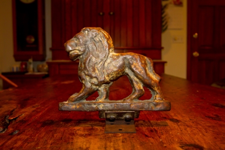 An antique bronze lion statue photographed on an old wooden table.の写真素材