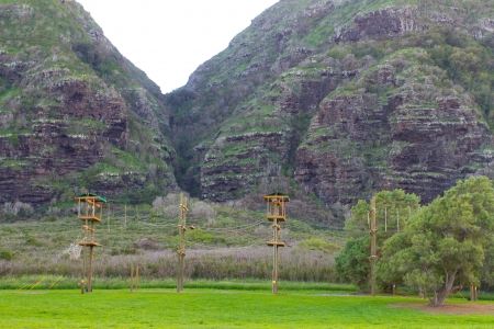 A camp on the north shore of Oahu in Hawaii has a high ropes stunt course for training and fun among the tropical vegetation and hills in the background.の写真素材