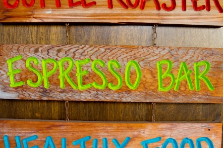 A handmade wood sign on a wood background is carved out and painted showing the words espresso bar in green letters.の写真素材