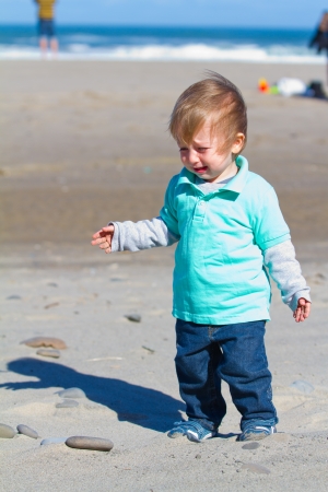 A child cries and looks sad while playing at the beach.の写真素材