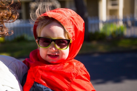 A young boy wears his sunglasses while walking back from the beach with his mom on a cool looking out of focus street.の写真素材
