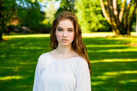 A beautiful young girl poses for a fashion style portrait outdoors at a park with natural lighting.の写真素材