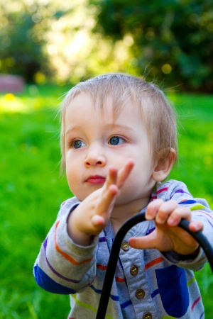 A very curious one year old toddler boy explores his backyard and plays with interesting things among the grass and plants.の写真素材