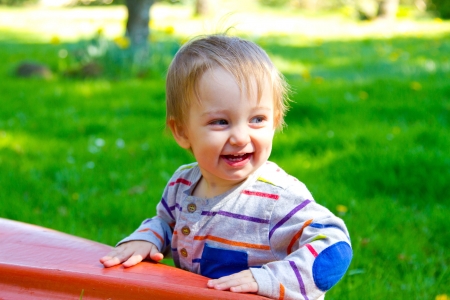 A very curious one year old toddler boy explores his backyard and plays with interesting things among the grass and plants.の写真素材
