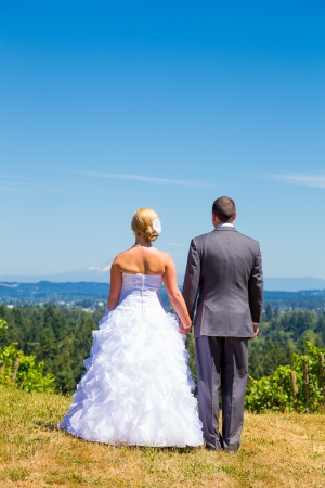 A bride and groom enjoy a view of mount hood in the background from this high elevation winery vineyard in Oregon just outside of Portland.の写真素材