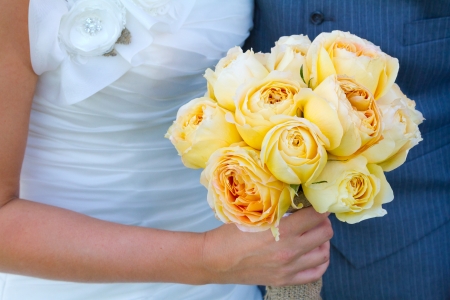 Bride and groom together while the bride holds her bouquet of flowers at her side.の写真素材