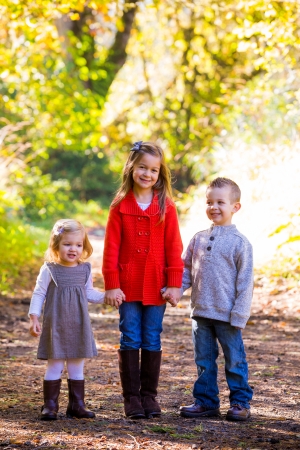 Three children stand together outdoors for a family Christmas holidays photo of the two girls and one boy.の写真素材