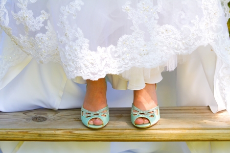 Blue wedding shoes shown to the camera by the bride as she lifts up the bottom of her dress on her wedding day.の写真素材
