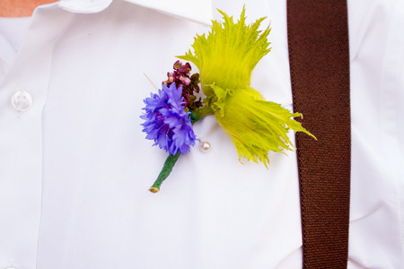 Caucasian groom wearing a boutineer made from a filbert nut flower on his wedding day.