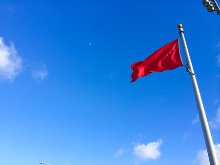 Red flag and blue sky waving in the wind in this simple abstract.の写真素材