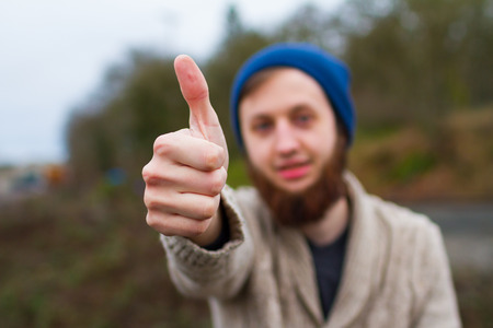 Man giving a thumbs up sign wearing a blue hat.