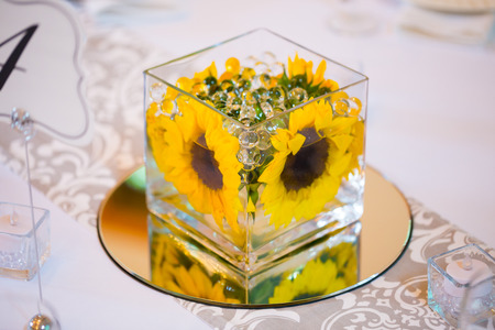 Flowers in glass on the tables for the centerpieces at this indoor wedding reception.の写真素材