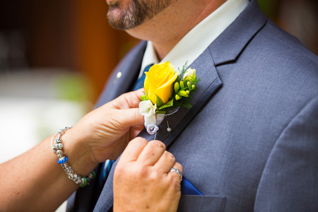 Mom pins the boutineer on groom on his wedding day.