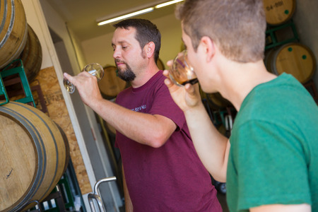 Eugene, OR, USA - July 17, 2014: Master brewer and employee sampling and tasting limited edition bourbon barrel aged beers at Oakshire Brewing.のeditorial素材