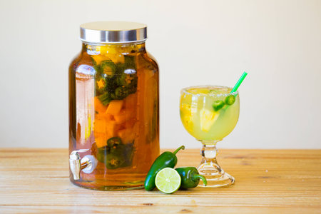 Tequila infused with jalapeno peppers in a tea jar at a restaurant bar.の写真素材