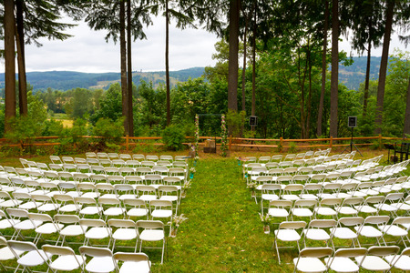 Wedding ceremony at an outdoor venue with grass, trees, and white chairs.の写真素材