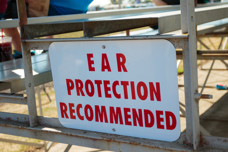 WOODBURN, OR - SEPTEMBER 27, 2015: Sign reads ear protection recommended in the spectator bleachers at the NHRA 30th Annual Fall Classic at the Woodburn Dragstrip.のeditorial素材