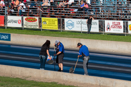 WOODBURN, OR - SEPTEMBER 27, 2015: Track workers clean up after a crash at the NHRA 30th Annual Fall Classic at the Woodburn Dragstrip.のeditorial素材