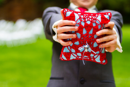 Rings tied to a pillow with the ring bearer holding them out.の写真素材