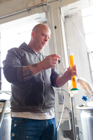 EUGENE, OR - NOVEMBER 4, 2015: Head brewmaster Brandon Woodruff checking the original gravity of an...