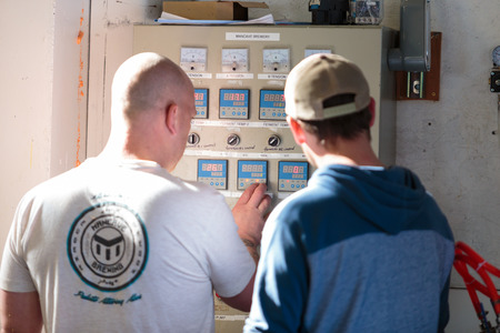 EUGENE, OR - NOVEMBER 4, 2015: Brewery co-owners Brandon Woodruff and Wes Gunderson setting fermenter temperatures at the startup craft brewery Mancave Brewing.のeditorial素材
