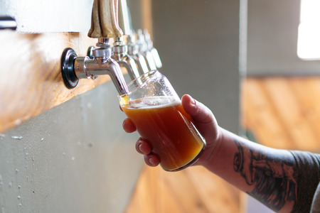 EUGENE, OR - NOVEMBER 4, 2015: Bartender and brewery co-owner Brandon Woodruff pouring Exalted IPA on tap at the startup craft brewery Mancave Brewing.のeditorial素材