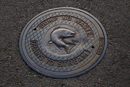 EUGENE, OR - NOVEMBER 21, 2015: Storm drain cover reads dump no waste, drains to stream in an effort to protect the water in local rivers and streams.のeditorial素材