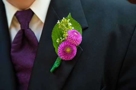 Groom wearing a pink and green boutineer on his tux jacket at a weddingの写真素材