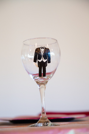 Tux painted wine glass for the groom at a wedding reception.の写真素材