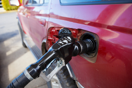 PORTLAND, OR - FEBRUARY 2, 2016: Gas station pump in a red automobile while receiving a fill in Oregon.のeditorial素材