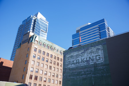 PORTLAND, OR - FEBRUARY 2, 2016: Downtown PDX office buildings against a parking sign.のeditorial素材