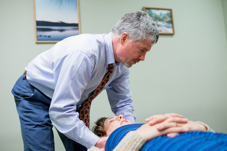 SPRINGFIELD, OR - AUGUST 20, 2014: Chiropractor adjusting the spine of an adult woman in a medical patient room.のeditorial素材