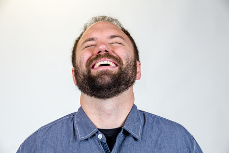Man in his mid-30's poses for a studio portrait with a semi white background.
