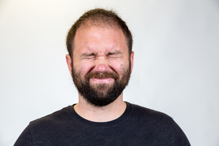 Man in his mid-30's poses for a studio portrait with a semi white background.