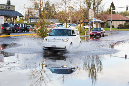 EUGENE, OR - MARCH 20, 2016: Automobile driving through a large puddle on the University of Oregon campus after torrential rainstorms moved through Eugene.のeditorial素材