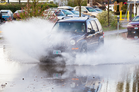 EUGENE, OR - MARCH 20, 2016: Automobile driving through a large puddle on the University of Oregon campus after torrential rainstorms moved through Eugene.のeditorial素材